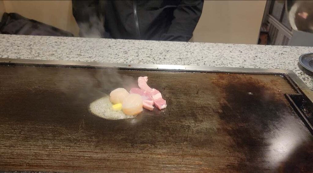 Pork sirloin and scallops being cooked on the grill for yamaimo-yaki dish at Okonomiyaki Mizuno in Osaka.