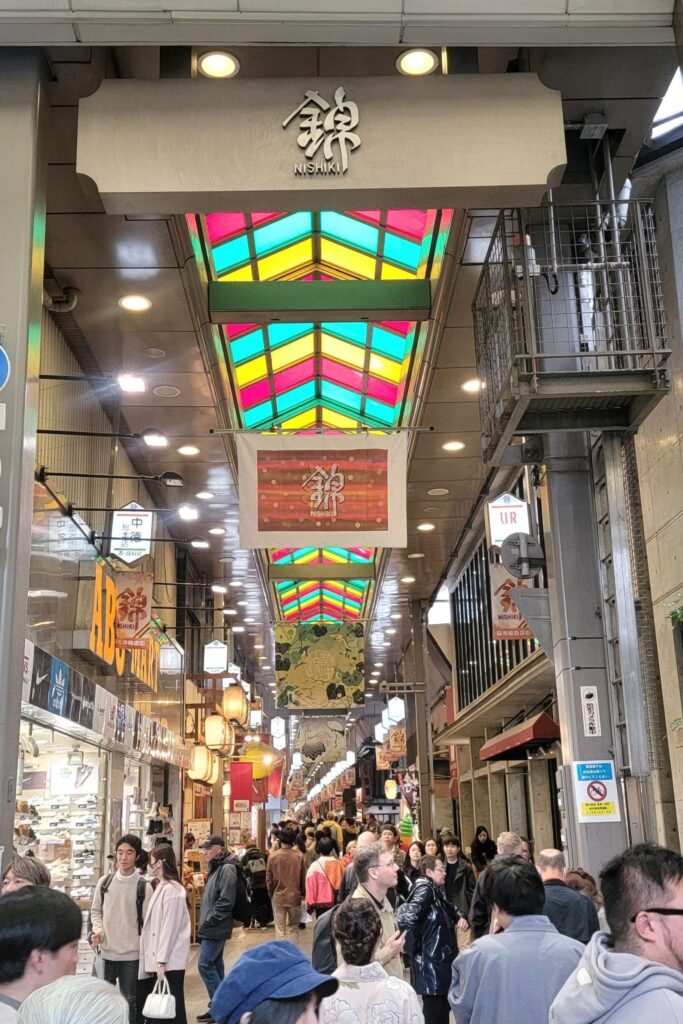 One of the Nishiki market entrance with sign above and many people.