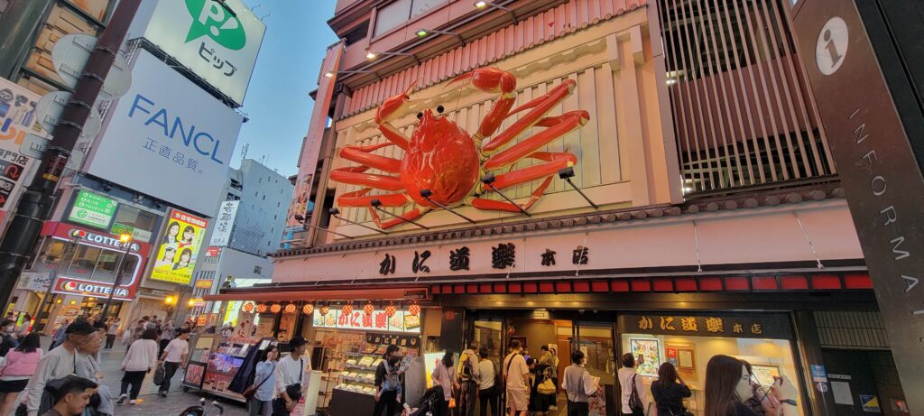 Exterior of Kani Doraku Main Branch restaurant in Osaka with large, red moving crab above entrance.