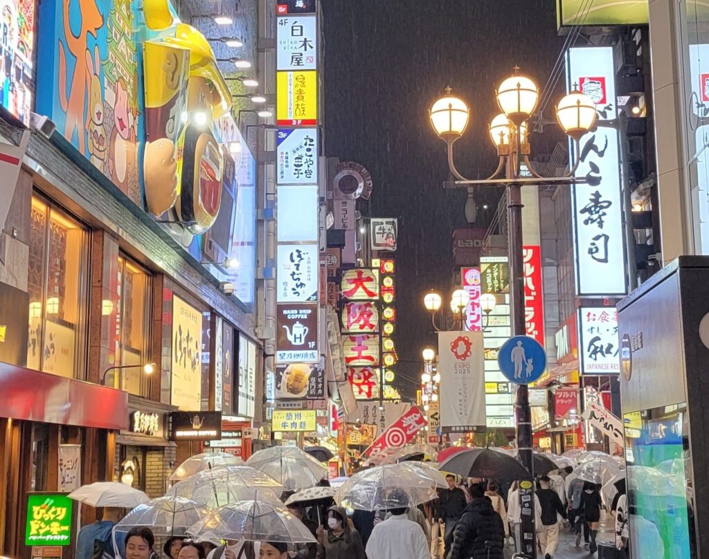 Photo in Dotonbori in Osaka, Japan's Kitchen, on a rainy night with crowds of people and lights.