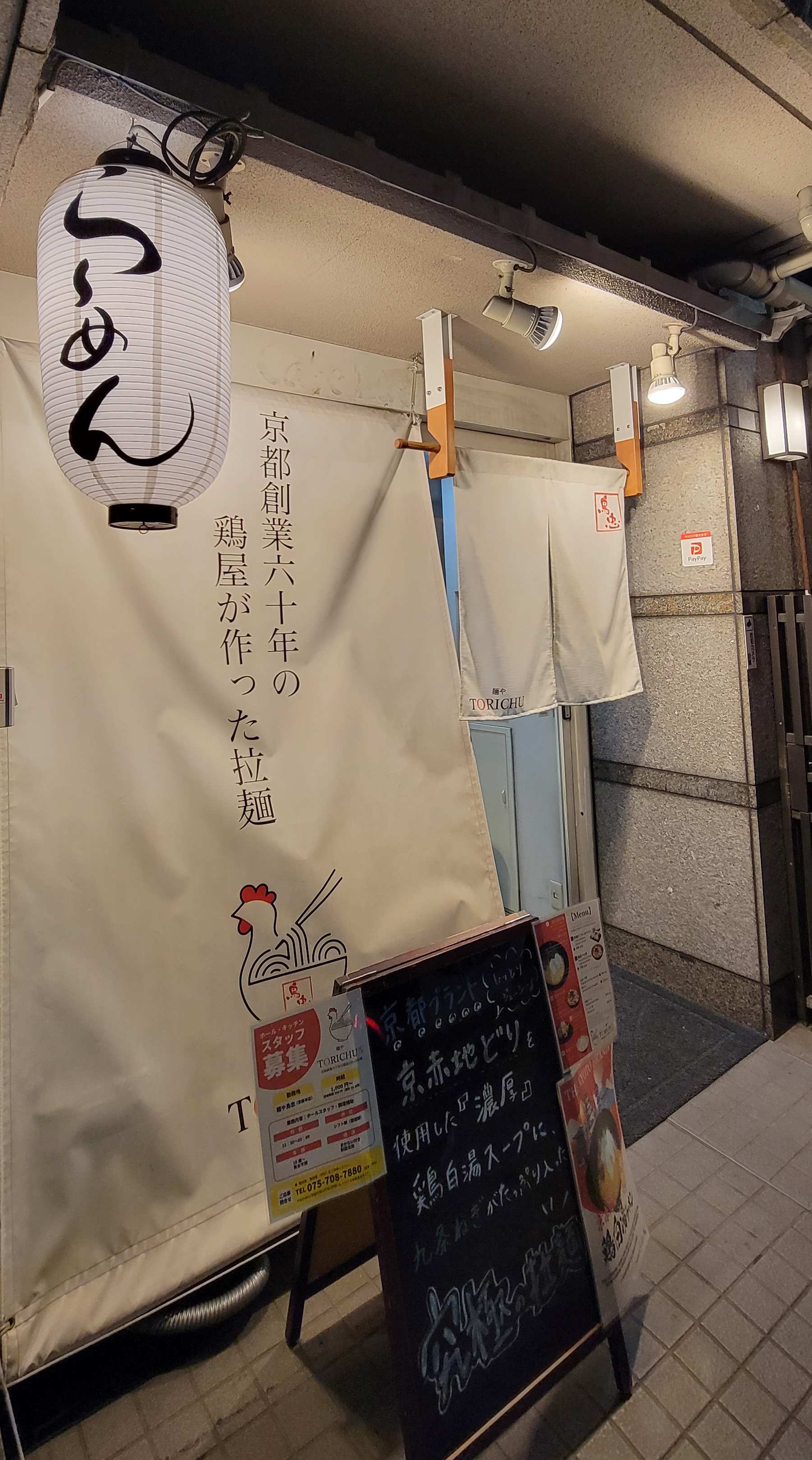 Exterior of Torichu restaurant in Kyoto with paper lantern and menu.