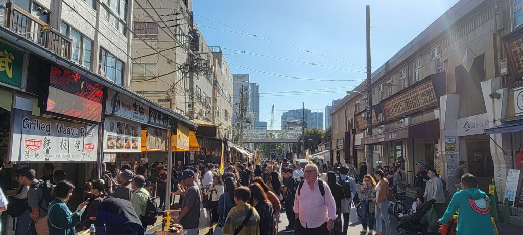 A sunny day at Tsukiji Outer Market in Tokyo with many people.