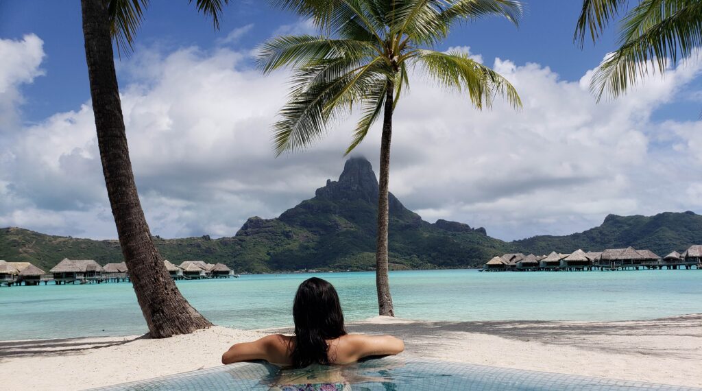 Woman looking at Mount Otemanu and beautiful view from the infinity pool at InterContinental Bora Bora & Thalasso Spa.