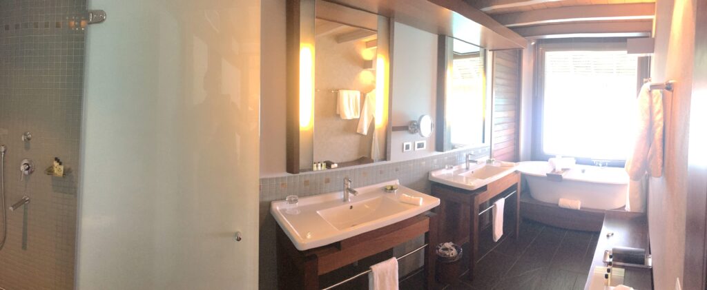 Bathroom in overwater villa at InterContinental Bora Bora & Thalasso Spa with double sinks, shower, tub, robes.