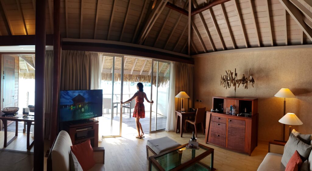 Woman opening the sliding doors in the living room of an overwater villa at the InterContinental Bora Bora & Thalasso Spa.