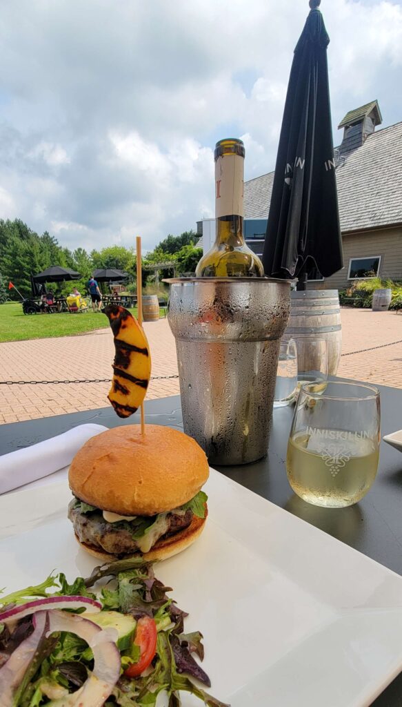 Peach burger and wine from Inniskillin Winery Niagara Estate Grill, one of our favourite Niagara-on-the-Lake restaurants with a beautiful view of vineyards, on a sunny day.