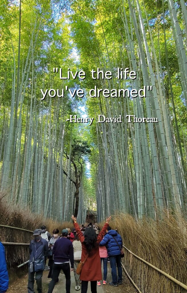 "Live the life you've dreamed" quoted by Henry David Thoreau on a picture of woman with arms up in Arashiyama Bamboo Forest in Kyoto.