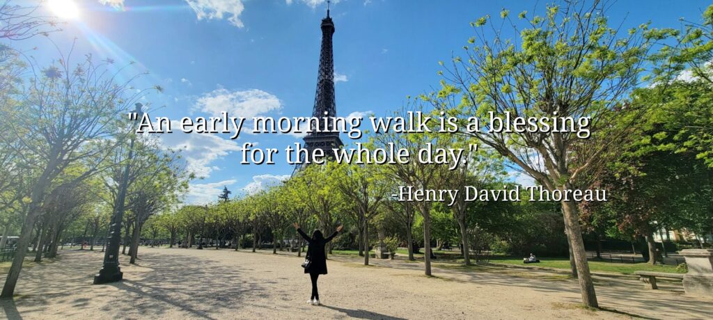 Woman in park in Paris with trees and eiffel tower in background with "An early morning walk is a blessing for the whole day" quote from Henry David Thoreau.