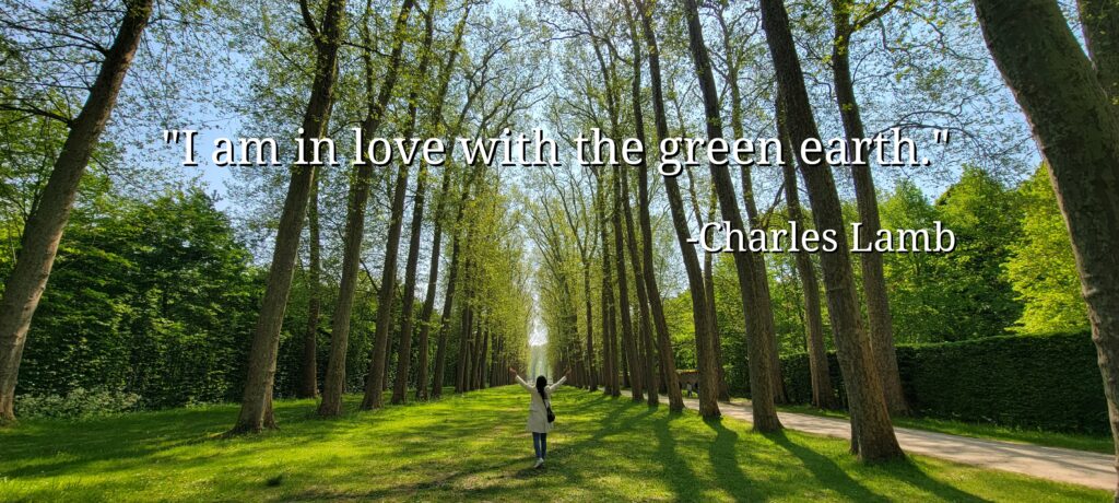 "I am in love with the green earth" quote by Charles Lamb on a picture of a woman forest bathing on the estate of the Palace of Versailles in France.